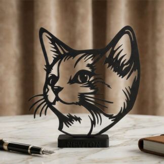 Silueta decorativa de cabeza de gato en 3D color negro mate con el nombre personalizado de la mascota en la base, colocado sobre una mesa moderna