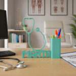 Organizador de bolígrafos personalizado en color azul mate con nombre de médico impreso en 3D sobre un escritorio de clínica minimalista.